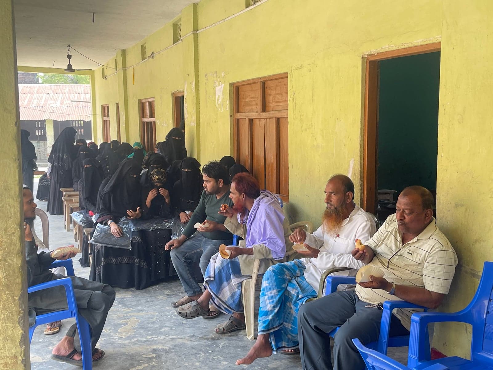 Program participants sit together along a covered corridor.